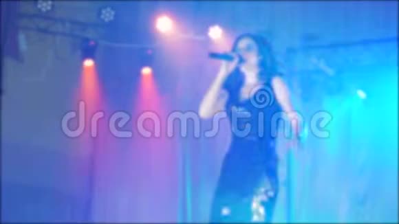 歌手女孩黑发唱模糊背景夜美丽的光与麦克风慢动作视频歌手视频的预览图