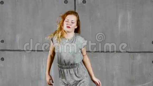 年轻的金发女郎穿着灰色衣服在墙边表演视频的预览图