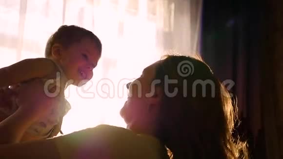 母亲通过阳光把儿子抱在家里在慢动作中玩好玩的笑爸爸视频的预览图