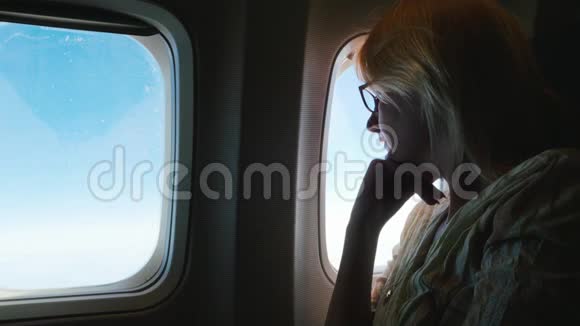 一个忧郁的女人坐飞机看着窗外侧视剪影视频的预览图
