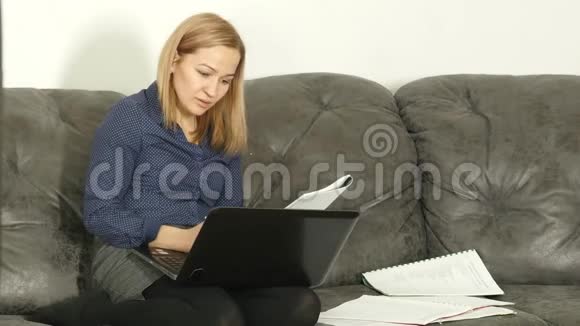 在沙发上学习的女人带着工作簿和笔记本电脑家庭在线教育4公里视频的预览图