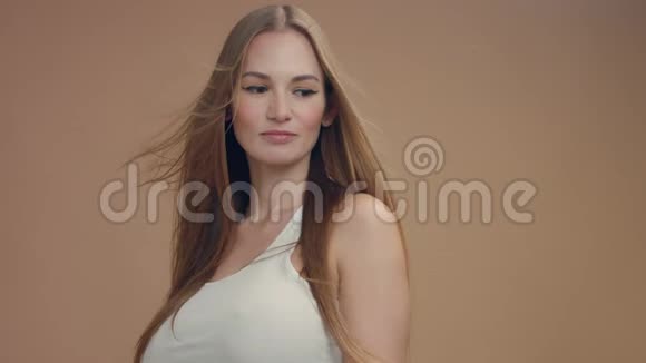 米色背景的摄影棚美女模特风吹头发视频的预览图