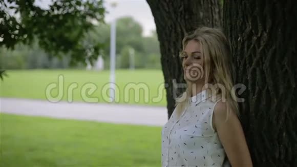 一个女孩站在一棵大树下在一个多风的夏天天气视频的预览图