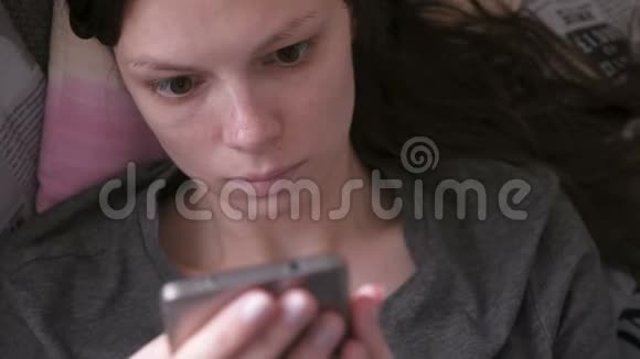 担心女人躺在沙发上用手机读东西特写的脸视频的预览图