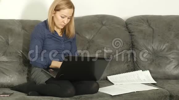 在沙发上学习的女人带着工作簿和笔记本电脑家庭在线教育4公里视频的预览图