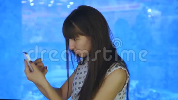 年轻女子在海洋馆玩口袋妖怪使用智能手机女孩玩流行的智能手机游戏捕捉视频的预览图