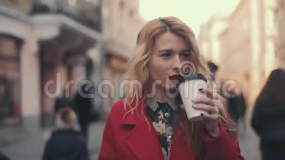 商务女性穿着红色外套带着咖啡在城市里散步并通过智能手机phablet进行交流稳住摄像机视频的预览图