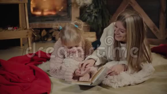 圣诞快乐新年快乐美丽的家庭在圣诞节的内部年轻漂亮的母亲给她读书视频的预览图