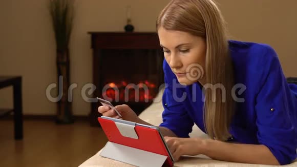 美丽迷人的年轻女子躺在沙发上用信用卡在网上买东西00327视频的预览图