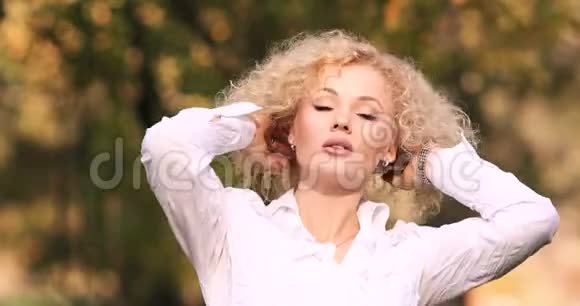 美丽的金发女人在秋天公园散步视频的预览图