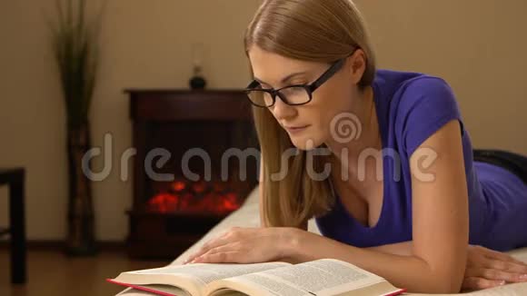 年轻漂亮的女人戴着眼镜躺在沙发上看书00347视频的预览图