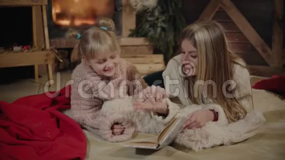 圣诞快乐新年快乐美丽的家庭在圣诞节的内部年轻漂亮的母亲给她读书视频的预览图