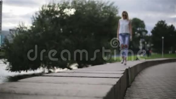 一个穿着时髦的女孩在刮风的天气里在河边散步视频的预览图