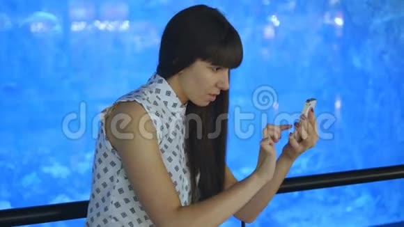 年轻女子在海洋馆玩口袋妖怪使用智能手机女孩玩流行的智能手机游戏捕捉视频的预览图