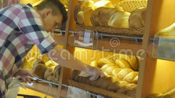 人们在超市里挑选一个新鲜的面包年轻人从架子上拿了一条面包闻着视频的预览图