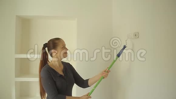 一个白人女人在公寓的墙上画一幅画视频的预览图