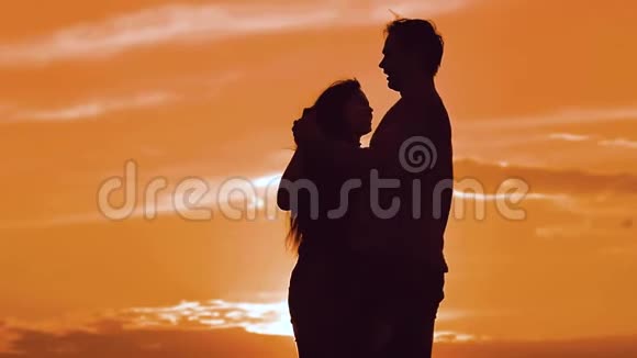 一对幸福的年轻夫妇的剪影男女在日落时分在外面缓慢地跳舞一对享受大自然的夫妇视频的预览图