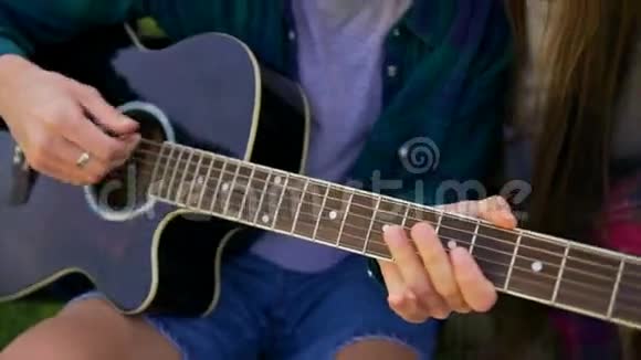 四个朋友正在拥抱弹吉他在日落时在户外唱歌视频的预览图