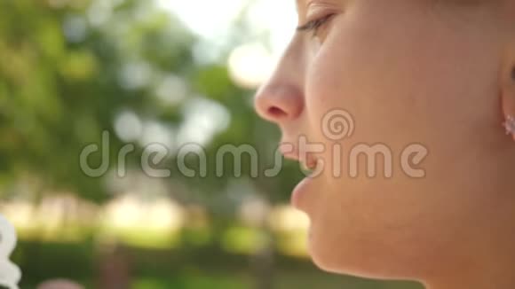 小女孩近距离吹肥皂泡慢动作春天夏天美丽的女孩在公园里吹肥皂泡视频的预览图
