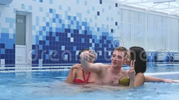 三个快乐的年轻朋友在游泳池里自拍视频的预览图