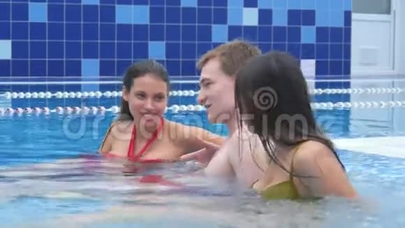 两个美女和一个年轻人在游泳池里的按摩浴缸里聊天和放松视频的预览图