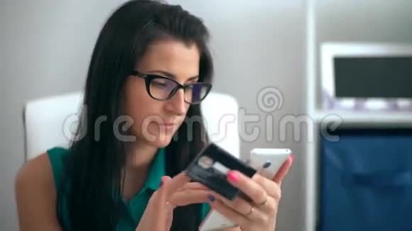 女性在使用智能手机输入数据时另一方面持信用卡视频的预览图