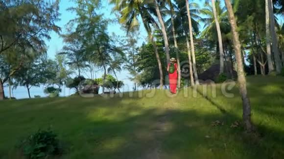 那个女人背着背包走路岛上高大的棕榈树魁克岛的富穿红色连衣裙的女人视频的预览图