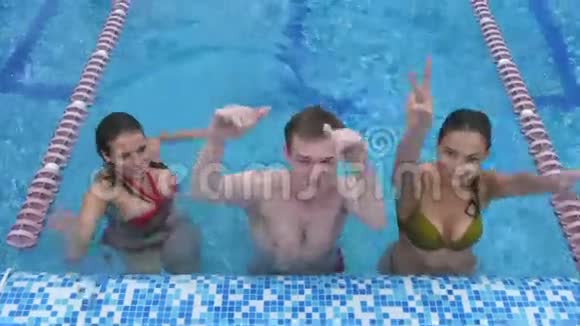 两个快乐的年轻女人和一个在游泳池里玩的年轻人视频的预览图