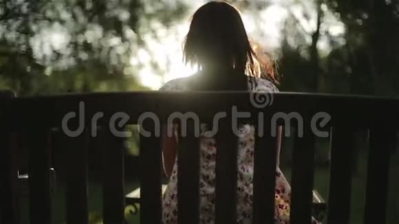 夕阳下一个黑发女人坐在长凳上视频的预览图