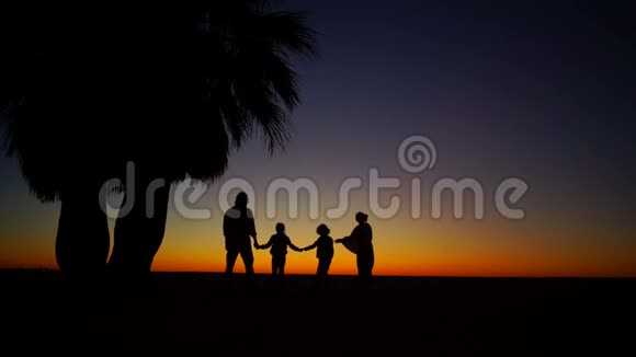 浪漫的家庭在海边漫步一个孩子直奔镜头的剪影儿童恶作剧视频的预览图