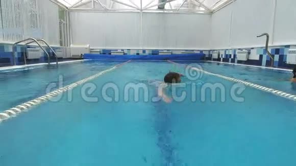 两个微笑的年轻女子在不同的泳道游泳一个年轻男子在泳道中间爬行视频的预览图