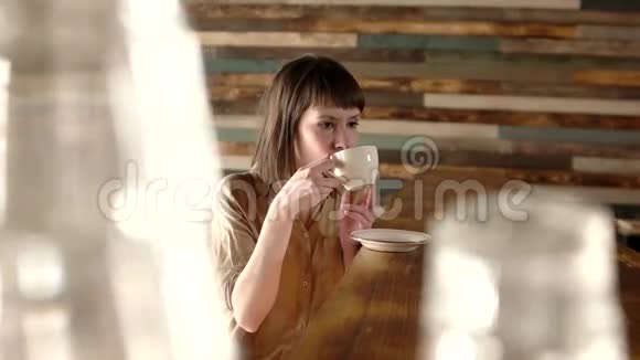年轻的美女浪漫的女人在晨光中喝热茶或咖啡快乐放松的女孩享受温暖的杯子视频的预览图