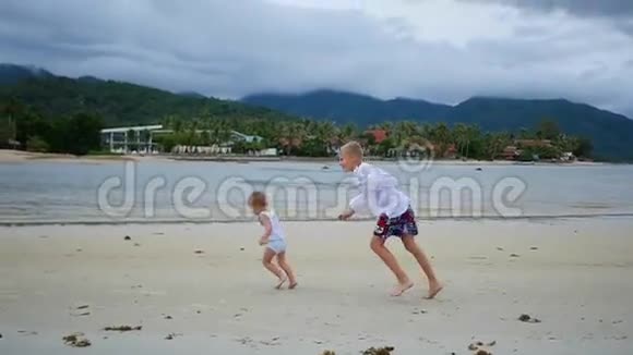 孩子们欢快地沿着海滩奔跑形成一片浪花视频的预览图