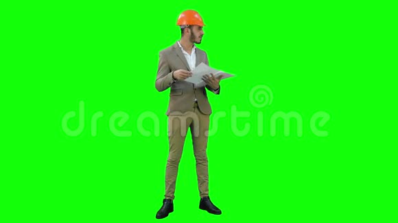 年轻的建筑师戴着头盔在绿色屏幕上查看施工图Chroma键视频的预览图