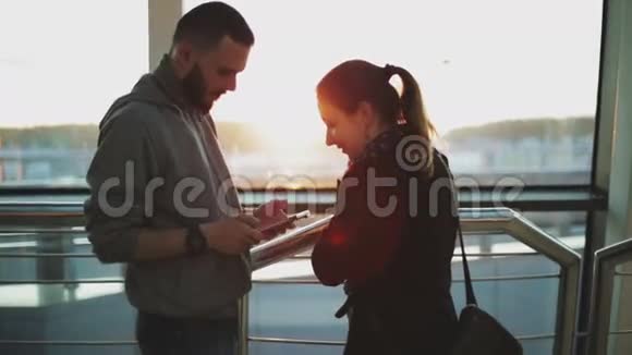 一个男孩和一个女孩站在机场的窗户附近视频的预览图