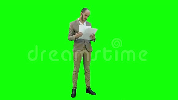严肃的年轻经理站在一个绿色的屏幕上用彩色键阅读文件视频的预览图