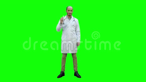 微笑的医生穿着白色外套指着药瓶看着绿色屏幕上的相机Chroma键视频的预览图