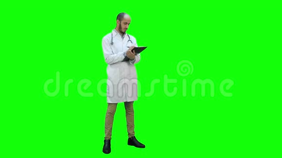 男医生穿着白色外套在绿色屏幕上填写病人表格Chroma键视频的预览图
