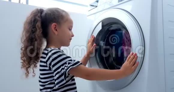 可爱的孩子在洗衣机里看气缸旋转机概念洗衣机工业视频的预览图