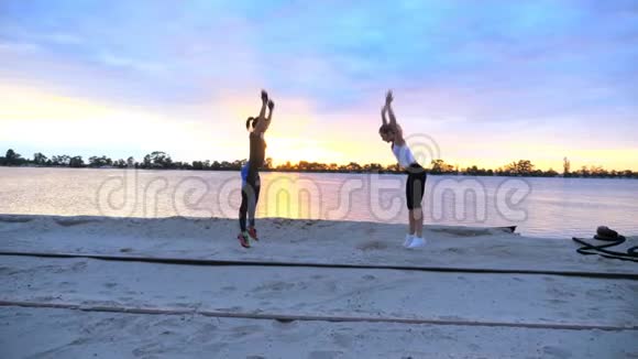 美丽苗条的年轻女性从事健身跳跃表演力量练习俯卧撑在黎明日出在视频的预览图
