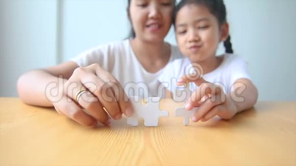4个亚洲小女孩和妈妈玩拼图游戏视频的预览图