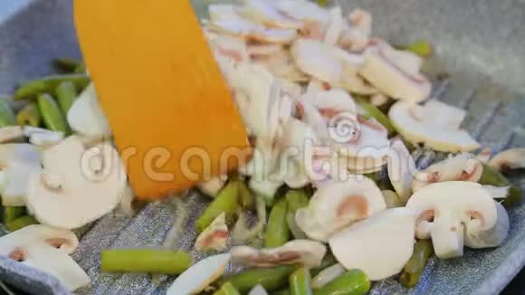 一个女人在煎锅里把绿豆和蘑菇混合在一起视频的预览图
