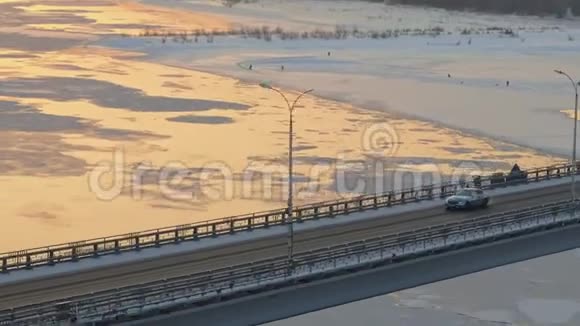 空中追踪独自一人的汽车穿过一座桥穿过冬天的河流浮冰视频的预览图