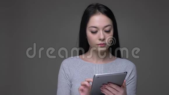 用平板电脑为年轻漂亮的黑发白种人女性拍摄特写镜头并用绿色屏幕拍摄视频的预览图