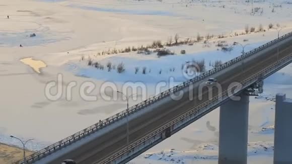 空中追踪独自一人的汽车穿过一座桥穿过冬天的河流浮冰视频的预览图