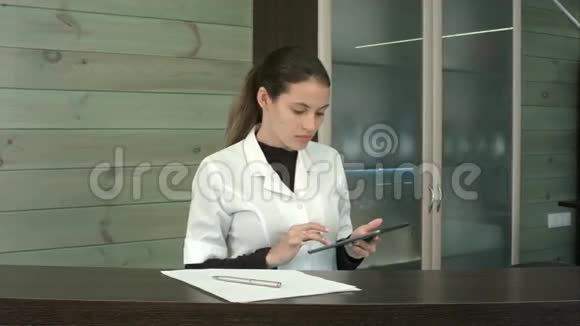 微笑的水疗接待员把她的平板电脑放在一边迎接客户视频的预览图