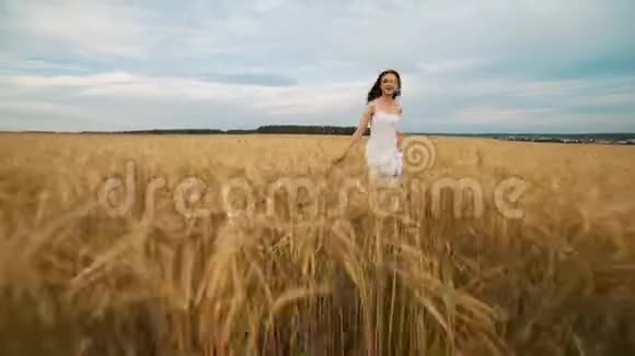 户外美女享受大自然美丽的少女模特穿着白色连衣裙在春天的田野上奔跑阳光明媚视频的预览图