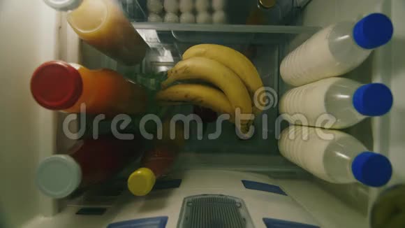 孩子从冰箱里拿出一根香蕉简单的水果小吃从冰箱里看到的高角度视频的预览图