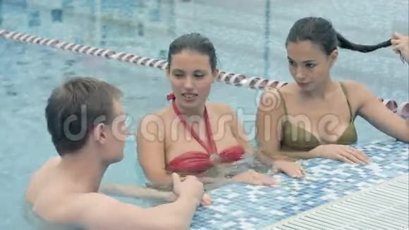 两个美女在游泳池里和一个年轻人说话视频的预览图