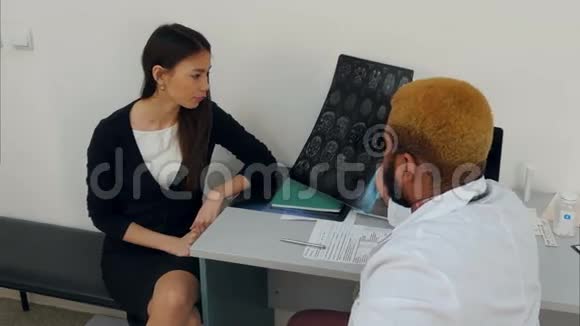 男性医生向年轻女性患者解释脑部X光检查结果视频的预览图